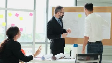 Mühendis ve mimarlardan oluşan bir ekip, proje planlarını modern bir ofiste tartışmak için Beyin Fırtınası 'nda toplanıyor. Ağır çekim. Bir plandan bahset..