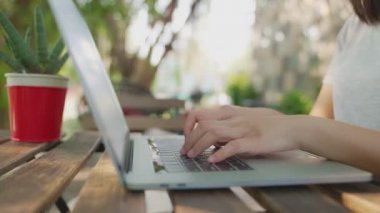 Yakın el ve parmaklar masanın üzerine klavye yazıyorlar. İnternet kampı ağ teknolojisini kullanarak evde, kafede ya da parkta çalışmak. Yeni normal bir hayat. Güzel yeşil ağaç arkaplanı