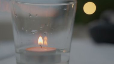 Yumuşak odak ya da bulanık video. Romantik ışığın gece esmesini engellemek için bir bardak suya mum yak. Parlak ışıkları ve güzel turuncu bir bokeh 'i var..