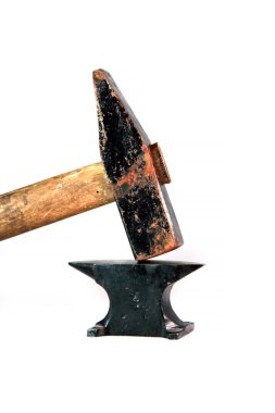 Çok küçük bir siyah örs üzerinde büyük paslı çekiç. 