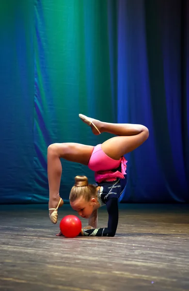 Girl on the stage performs gymnastic exercise ball. — Stock Photo, Image