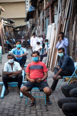 MUMBAI / INDIA - 9 Nisan 2020: COVID-19 Coronavirus 'a karşı önleyici bir önlem olarak devlet tarafından ülke çapında kilit altına alınan Mohmadi eski kereste pazarında kapalı dükkanlarda oturan işçiler.