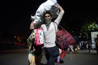 MUMBAI / INDIA - 7 Mayıs 2020: COVID-19 Coronavirus 'a karşı önleyici bir önlem olarak aile üyeleri ile birlikte Thane' deki evlerine giderken yolda yürüyen göçmen işçiler.