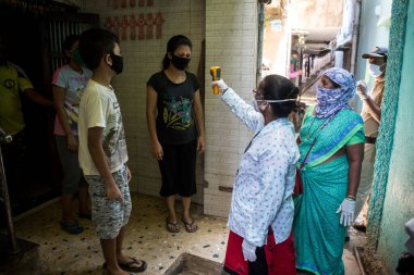 MUMBAI/INDIA - APRIL 26, 2020: Health workers wearing protective gear monitor body temperature of people at a Dharavi slum during the government-imposed nationwide lockdown as a preventive measure against the COVID-19 coronavirus.