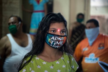 MUMBAI/INDIA - APRIL 26, 2020: Health workers wearing protective gear monitor body temperature of people at a Dharavi slum during the government-imposed nationwide lockdown as a preventive measure against the COVID-19 coronavirus.