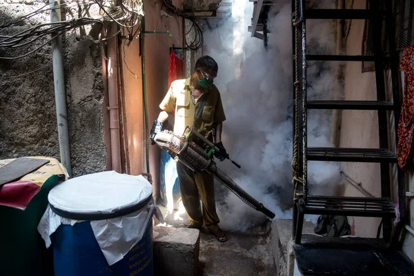 MUMBAI/INDIA - APRIL 28, 2020: A civic worker wearing a face mask use fogging machine to disinfect slum area at Khar, as a preventive measure against the COVID-19 coronavirus.