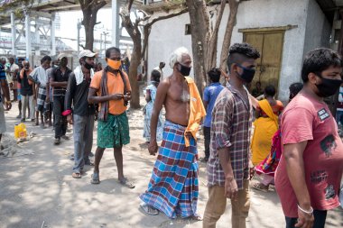 MUMBAI / INDIA - 29 Nisan 2020: Koronavirüse karşı önleyici bir önlem olarak ülke çapındaki tecrit sırasında Dharavi gecekondu mahallesindeki gönüllülerden yiyecek almak için evsizler ve işsizler kuyrukta bekliyor.