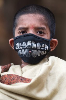 MUMBAI / INDIA - 2 Mayıs 2020: COVID-19 Coronavirus nedeniyle ülke çapındaki tecrit sırasında koruyucu maske takan bir çocuk.