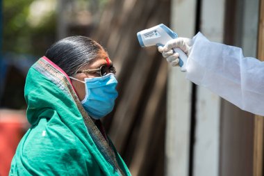 MUMBAI / INDIA - MAYIS 1, 2020: COVID-19 Coronavirus 'a karşı önleyici bir önlem olarak Kurla' daki COVID-19 Coronavirus test sürüşü sırasında kadınların vücut sıcaklığını izleyen sağlık çalışanı.
