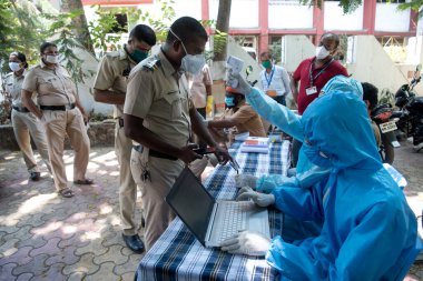 MUMBAI / INDIA - 3 Mayıs 2020: Göçmen işçiler, COVID -19 Coronavirüs 'e karşı önleyici bir önlem olarak ülke çapındaki tecrit sırasında evlerine dönebilmek için doktor sertifikaları almak üzere kuyrukta bekliyorlar