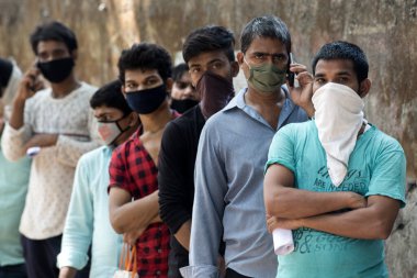 MUMBAI / INDIA - 3 Mayıs 2020: Göçmen işçiler, COVID -19 Coronavirüs 'e karşı önleyici bir önlem olarak ülke çapındaki tecrit sırasında evlerine dönebilmek için doktor sertifikaları almak üzere kuyrukta bekliyorlar