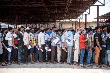 MUMBAI / INDIA - 6 Mayıs 2020: Göçmen işçiler COVID-19 Coronavirus 'a karşı önleyici bir önlem olarak ülke çapındaki tecrit süresince evlerine geri dönebilmek için doktor sertifikaları almak için kuyrukta bekliyorlar