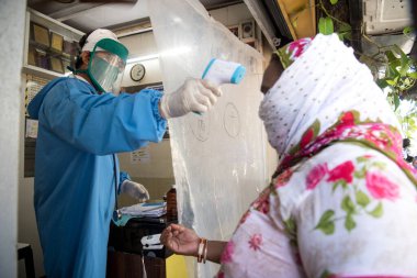 MUMBAI / INDIA - 7 Mayıs 2020: Koruyucu giysi giyen bir doktor, Dharavi gecekondu mahallesindeki bir klinikteki hastayı kontrol ediyor.