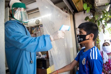 MUMBAI / INDIA - 7 Mayıs 2020: Koruyucu giysi giyen bir doktor, Dharavi gecekondu mahallesindeki bir klinikteki hastayı kontrol ediyor.