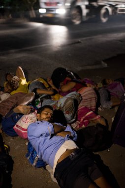 MUMBAI / INDIA - 9 Mayıs 2020: Göçmen işçiler, Coronavirus 'un yayılmasına karşı önleyici bir önlem olarak ülke çapındaki tecrit süresince Thane Bhiwandi karayolunda uyur..