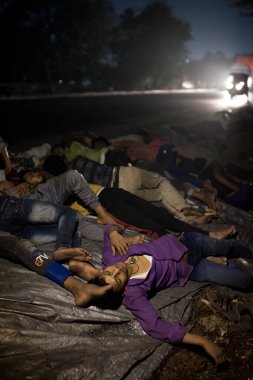 MUMBAI / INDIA - 9 Mayıs 2020: Göçmen işçiler, Coronavirus 'un yayılmasına karşı önleyici bir önlem olarak ülke çapındaki tecrit süresince Thane Bhiwandi karayolunda uyur..
