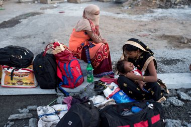 MUMBAI / INDIA - 9 Mayıs 2020: Göçmen işçiler, koronavirüsün yayılmasına karşı önleyici bir önlem olarak Bhiwandi otobanındaki eve dönüş yolculuklarında yolda oturuyorlar.
