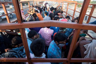 MUMBAI / INDIA - 9 Mayıs 2020: Göçmen işçiler, koronavirüsün yayılmasını önleyici bir önlem olarak Bhiwandi karayolundaki evlerine dönüş yolculuklarında bavullarıyla bir kamyona bindiler.