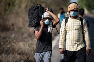 MUMBAI / INDIA - 9 Mayıs 2020: Göçmen işçiler, koronavirüsün yayılmasına karşı önleyici bir önlem olarak Bhiwandi karayolunda yurda dönüş yolculuklarında yürüyorlar.