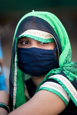 MUMBAI / INDIA - 11 Mayıs 2020: Yüz maskesi takan göçmen işçi, Coronavirus 'un yayılmasına karşı önleyici bir önlem olarak Bhiwandi otoyolunda evine dönüş yolunda oturuyor.