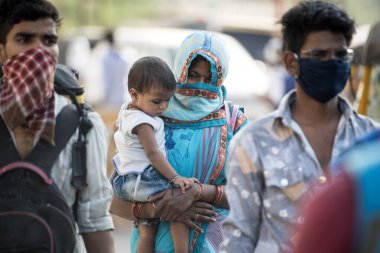 MUMBAI / INDIA - 11 Mayıs 2020: Göçmen işçiler, koronavirüsün yayılmasına karşı önleyici bir önlem olarak Bhiwandi otobanındaki eve dönüş yolculuklarında bavullarıyla birlikte yürüdüler.