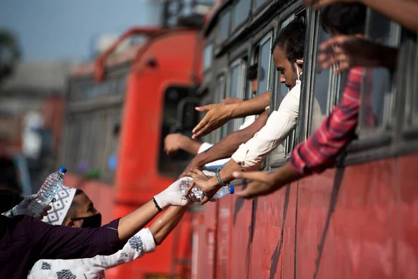 MUMBAI / INDIA - 11 Mayıs 2020: Gönüllüler, koronavirüsün yayılmasına karşı önleyici bir önlem olarak Bhiwandi otobanındaki göçmen işçilere su dağıtırlar.