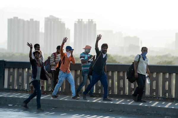 МУМБАЙ / ИНДИЯ - 11 мая 2020 года: Трудящиеся-мигранты, одетые в маску для лица, прогуливаются со своим багажом по шоссе Бхиванди по пути домой во время общенациональной изоляции в качестве меры пресечения распространения коронавируса.