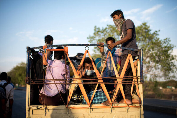 МУМБАЙ / ИНДИЯ - 11 мая 2020 года: Трудящиеся-мигранты поднимаются в темпе со своим багажом на шоссе Бхиванди по пути домой во время общенациональной изоляции в качестве профилактической меры против распространения коронавируса.