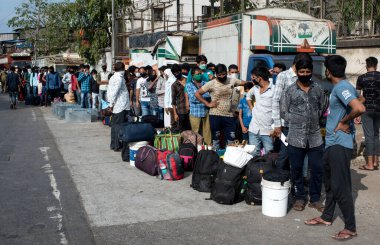 MUMBAI / INDIA - 13 Mayıs 2020: Göçmen işçiler, koronavirüsün yayılmasına karşı önleyici bir önlem olarak ülke çapındaki tecrit sırasında özel bir trene bindikleri için tren terminaline gitmek üzere otobüse binmek üzere kuyruğa girdiler