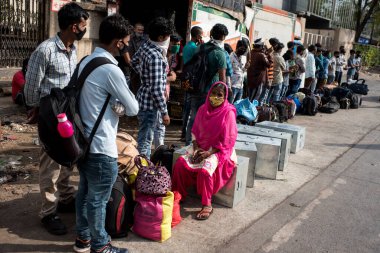 MUMBAI / INDIA - 13 Mayıs 2020: Göçmen işçiler, koronavirüsün yayılmasına karşı önleyici bir önlem olarak ülke çapındaki tecrit sırasında özel bir trene bindikleri için tren terminaline gitmek üzere otobüse binmek üzere kuyruğa girdiler