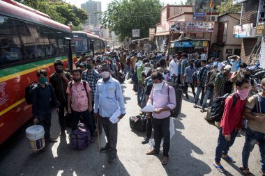 MUMBAI / INDIA - 13 Mayıs 2020: Göçmen işçiler Coronavirus 'un yayılmasına karşı önleyici bir önlem olarak Dharavi' deki özel bir trene bindikleri için onları tren terminaline götürmek üzere otobüs kuyruğunda bekliyorlar