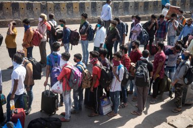 MUMBAI / INDIA - 13 Mayıs 2020: Göçmen işçiler Coronavirus 'un yayılmasına karşı önleyici bir önlem olarak Dharavi' deki özel bir trene bindikleri için onları tren terminaline götürmek üzere otobüs kuyruğunda bekliyorlar