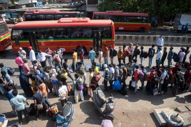 MUMBAI / INDIA - 13 Mayıs 2020: Göçmen işçiler Coronavirus 'un yayılmasına karşı önleyici bir önlem olarak Dharavi' deki özel bir trene bindikleri için onları tren terminaline götürmek üzere otobüs kuyruğunda bekliyorlar