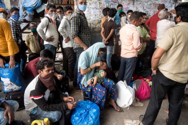 MUMBAI / INDIA - 13 Mayıs 2020: Göçmen işçiler, koronavirüsün yayılmasına karşı önleyici bir önlem olarak Bandra 'daki eve dönüş trenine bindikleri için tren terminalinin dışında oturuyorlar