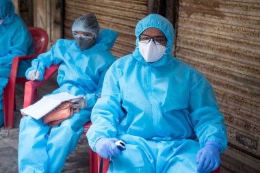 MUMBAI / INDIA - 14 Mayıs 2020: Coronavirus 'un yayılmasına karşı önleyici bir önlem olarak Dharavi gecekondu mahallesindeki COVID-19 Coronavirus test sürüşünde hastaları bekleyen tıp çalışanı.