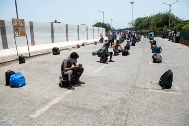 MUMBAI / INDIA - 14 Mayıs 2020: Göçmen işçiler, koronavirüsün yayılmasına karşı önleyici bir önlem olarak ülke çapındaki tecrit sırasında özel bir trene bindikleri için Bandra tren istasyonunda bavullarıyla kuyrukta oturuyorlar.