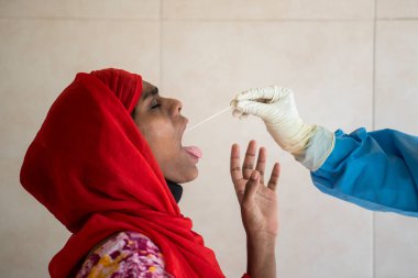 MUMBAI / INDIA - MAYIS 16, 2020: Bir tıbbi personel COVID-19 Coronavirus salgını sırasında bir kadından örnek alır..