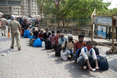 MUMBAI / INDIA - 16 Mayıs 2020: Göçmen işçiler, Coronavi 'nin yayılmasına karşı önleyici bir önlem olarak ülke çapındaki tecrit sırasında yerli yerlerini almak üzere özel bir trene bindikleri için Lokmanya Tilak tren istasyonuna girmek için kuyrukta bekliyor