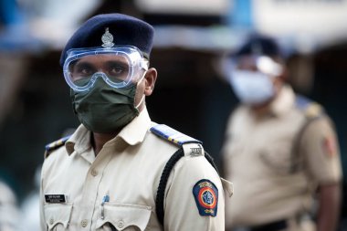 MUMBAI / INDIA - 20 Mayıs 2020: Surat maskesi takan Mumbai polisi, koronavirüsün yayılmasına karşı önleyici bir önlem olarak Bhendi pazarındaki bir kontrol noktasında nöbet tutuyor.