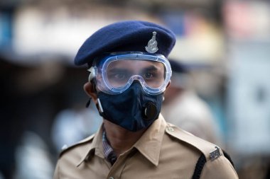 MUMBAI / INDIA - 20 Mayıs 2020: Surat maskesi takan Mumbai polisi, koronavirüsün yayılmasına karşı önleyici bir önlem olarak Bhendi pazarındaki bir kontrol noktasında nöbet tutuyor.