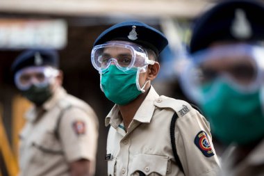 MUMBAI / INDIA - 20 Mayıs 2020: Surat maskesi takan Mumbai polisi, koronavirüsün yayılmasına karşı önleyici bir önlem olarak Bhendi pazarındaki bir kontrol noktasında nöbet tutuyor.
