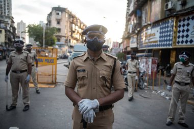 MUMBAI / INDIA - 20 Mayıs 2020: Surat maskesi takan Mumbai polisi, koronavirüsün yayılmasına karşı önleyici bir önlem olarak Bhendi pazarındaki bir kontrol noktasında nöbet tutuyor.