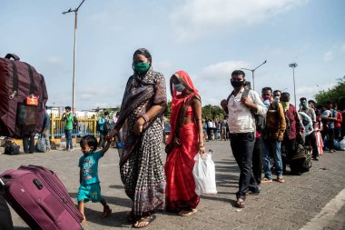 MUMBAI / INDIA - 21 Mayıs 2020: Göçmen işçiler, Coronavirus 'un yayılmasına karşı önleyici bir önlem olarak ülke çapındaki tecrit sırasında eve dönüş yolculuklarında özel bir trene bindikleri için Bandra tren istasyonunda kuyruğa girdiler