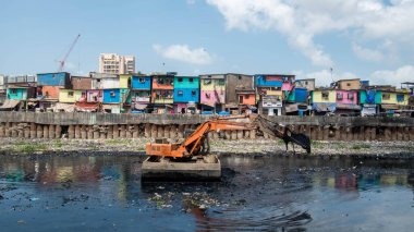 MUMBAI/INDIA - MAY 27, 2020: floating excavator cleaning waste material from the mithi river during pre-monsoon work by Mumbai Municipal Corporation at Gyaneshwar Nagar, Bandra (East clipart