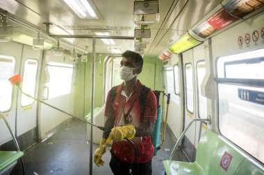 MUMBAI / INDIA - 28 Mayıs 2020: Bir işçi COVID-19 corona virüsüne karşı önleyici bir önlem olarak akıl sağlığına dezenfektan sıkarak, MMRDA koronavirüs salgını sırasında Mono demiryolu hizmetlerini halka yeniden açmaya hazırlanıyor.