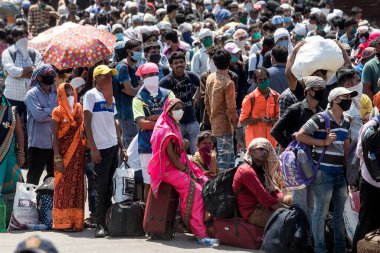 MUMBAI / INDIA - 26 Mayıs 2020: Göçmen işçiler, ülke çapındaki tecrit sırasında ülkeye dönüş yolculuklarına özel bir trene bindikleri için onları tren terminaline götürmek üzere bir otobüse binmek için kuyrukta bekliyor. 