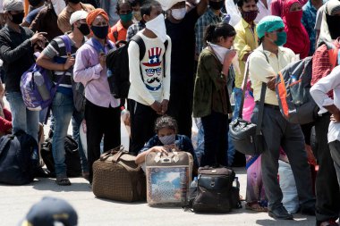 MUMBAI / INDIA - 26 Mayıs 2020: Göçmen işçiler, ülke çapındaki tecrit sırasında ülkeye dönüş yolculuklarına özel bir trene bindikleri için onları tren terminaline götürmek üzere bir otobüse binmek için kuyrukta bekliyor. 