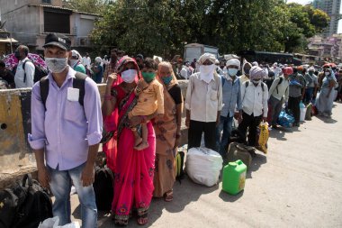 MUMBAI / INDIA - 26 Mayıs 2020: Göçmen işçiler aile üyeleriyle birlikte, önleyici tedbir olarak, ülke çapındaki tecrit sırasında özel bir trene bindikleri için onları tren istasyonuna götürmek üzere sıraya girdiler.