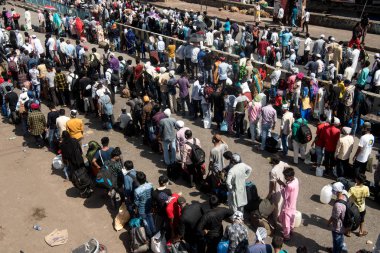 MUMBAI / INDIA - 26 Mayıs 2020: Göçmen işçiler, ülke çapındaki tecrit sırasında ülkeye dönüş yolculuklarına özel bir trene bindikleri için onları tren terminaline götürmek üzere bir otobüse binmek için kuyrukta bekliyor. 