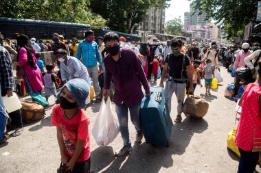 MUMBAI / INDIA - 26 Mayıs 2020: Göçmen işçiler aile üyeleriyle birlikte, önleyici tedbir olarak, ülke çapındaki tecrit sırasında özel bir trene bindikleri için onları tren istasyonuna götürmek üzere sıraya girdiler.